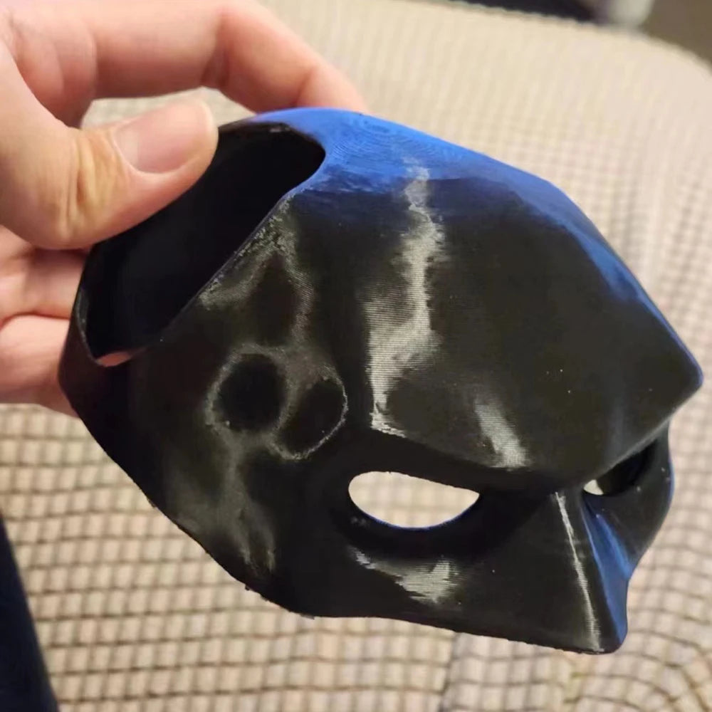 Black mask held by a hand on a textured surface