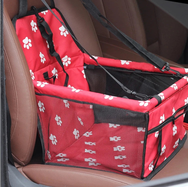 Red pet car seat with white paw prints on a brown car seat