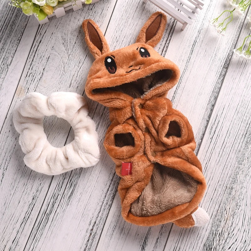 Brown plush animal costume on a wooden surface with a white scrunchie.
