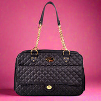 Black quilted handbag with gold accents on a pink background