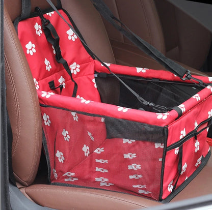 Red pet car seat with white paw prints on a brown car seat