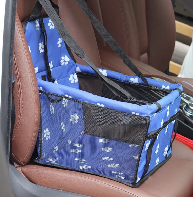 Blue pet carrier with white paw prints on a car seat